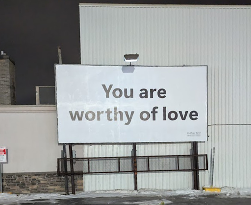 a billboard that is fully blank other than saying You are worthy of love. Has a very small name and phone number in the bottom right corner, I blured out the phone number