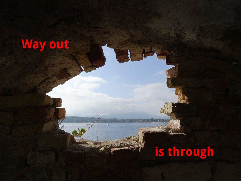 A view from some dungeon throug a hole broken in the wall, showing sunny seaview outside. Red lettes on the wall say "Way out is through"